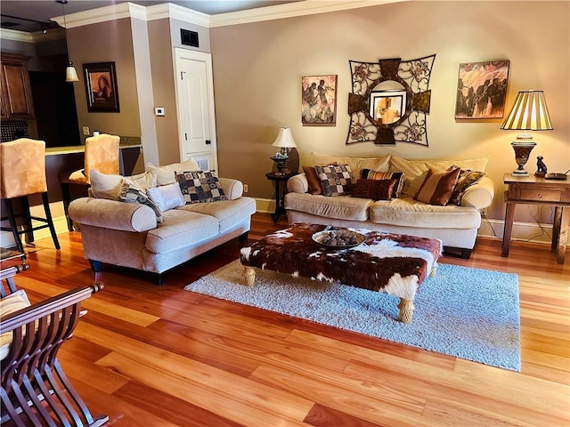 living room with baseboards, wood finished floors, visible vents, and crown molding