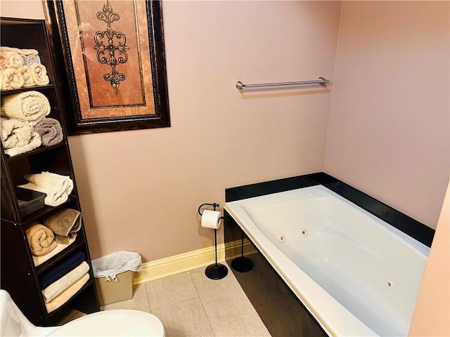 full bath with a jetted tub, tile patterned flooring, toilet, and baseboards