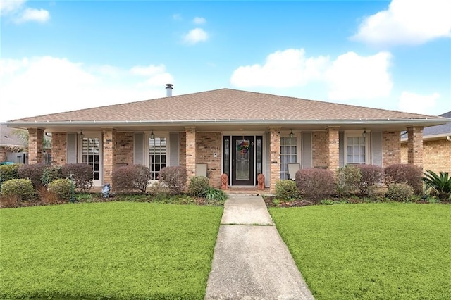 ranch-style home with a front lawn, roof with shingles, and brick siding