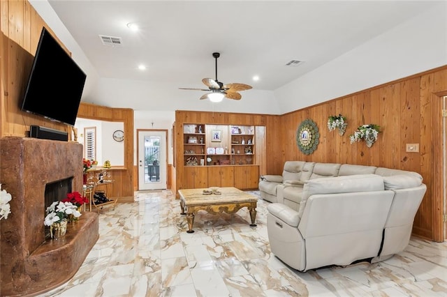 living room with marble finish floor, visible vents, wood walls, and a premium fireplace