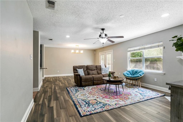 living area with visible vents, baseboards, wood finished floors, and ceiling fan with notable chandelier