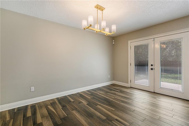 empty room featuring baseboards, dark wood-type flooring, french doors, a textured ceiling, and a notable chandelier