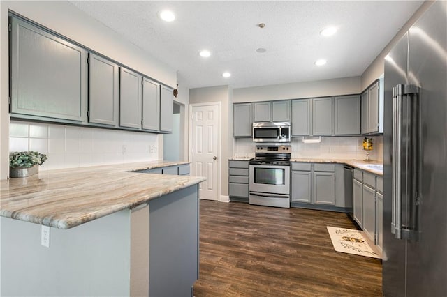 kitchen featuring gray cabinetry, recessed lighting, a peninsula, stainless steel appliances, and dark wood-style flooring