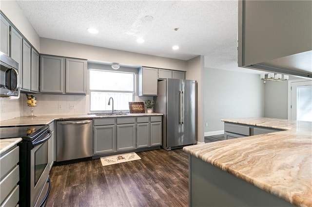 kitchen featuring a sink, gray cabinetry, dark wood-style flooring, and stainless steel appliances