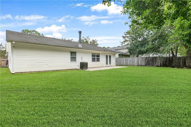 rear view of property featuring a yard, a patio, central AC, and a fenced backyard