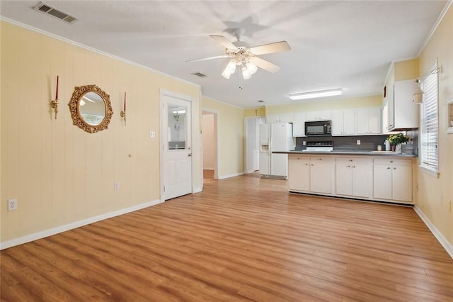 kitchen featuring black microwave, light wood-style flooring, a peninsula, white refrigerator with ice dispenser, and visible vents