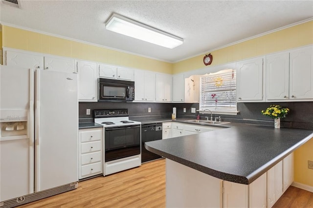 kitchen with a peninsula, a sink, white cabinetry, black appliances, and dark countertops