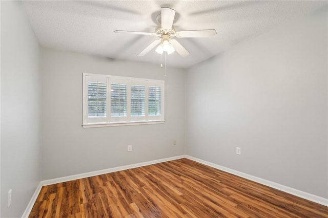 spare room with a textured ceiling, ceiling fan, wood finished floors, and baseboards