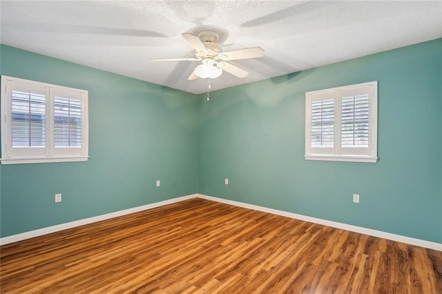 spare room with a wealth of natural light, baseboards, and wood finished floors