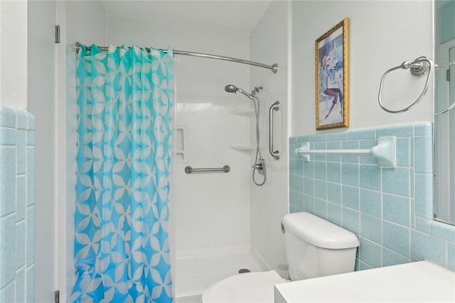 bathroom featuring curtained shower, toilet, vanity, tile walls, and wainscoting