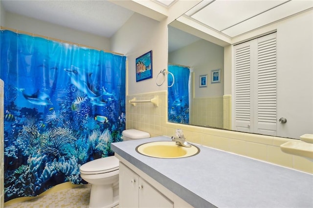 full bathroom with curtained shower, toilet, vanity, tile walls, and wainscoting