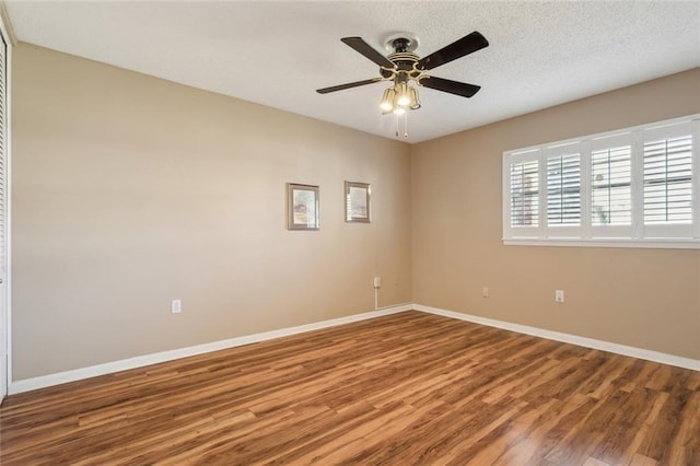 spare room with ceiling fan, a textured ceiling, baseboards, and wood finished floors