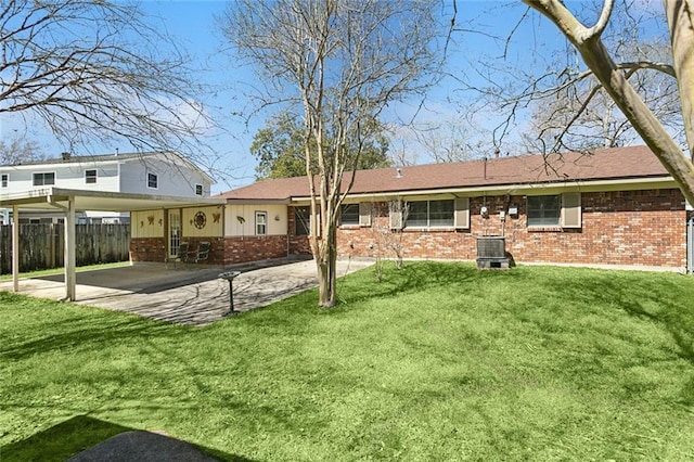 rear view of house with a yard, fence, a carport, and brick siding