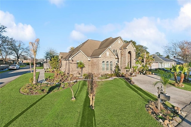 view of front facade featuring concrete driveway, brick siding, and a front lawn