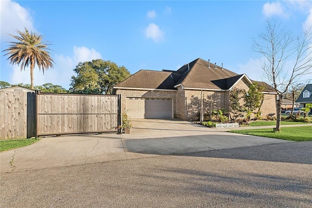 view of front of house featuring brick siding, concrete driveway, a gate, fence, and a garage