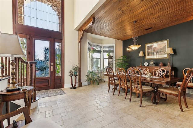 interior space featuring stone tile floors, visible vents, baseboards, a towering ceiling, and wooden ceiling