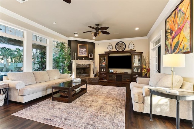 living area with visible vents, ceiling fan, dark wood-style flooring, crown molding, and a high end fireplace