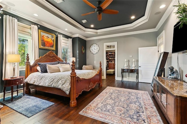 bedroom with a tray ceiling, dark wood-style flooring, visible vents, and crown molding