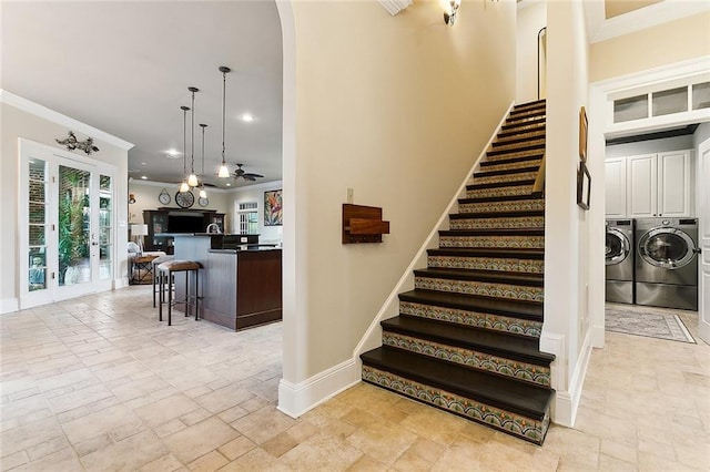 stairs with baseboards, stone tile floors, washing machine and dryer, and crown molding