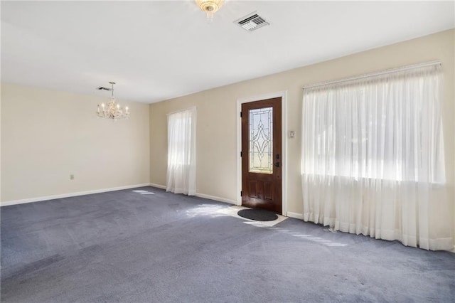 carpeted foyer with visible vents, a notable chandelier, and baseboards