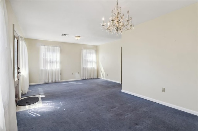 spare room featuring a chandelier, dark carpet, visible vents, and baseboards