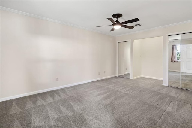 unfurnished bedroom featuring crown molding, carpet floors, visible vents, and multiple closets