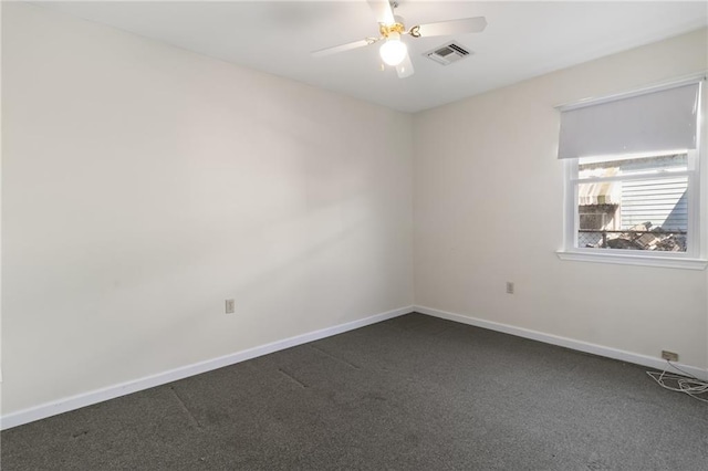 unfurnished room with a ceiling fan, visible vents, dark carpet, and baseboards