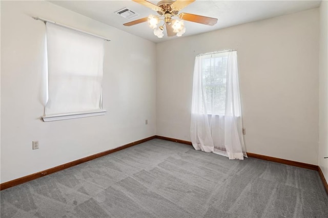 carpeted empty room featuring a ceiling fan, visible vents, and baseboards