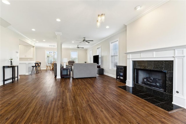 unfurnished living room featuring dark wood-style floors, crown molding, a fireplace, a ceiling fan, and baseboards