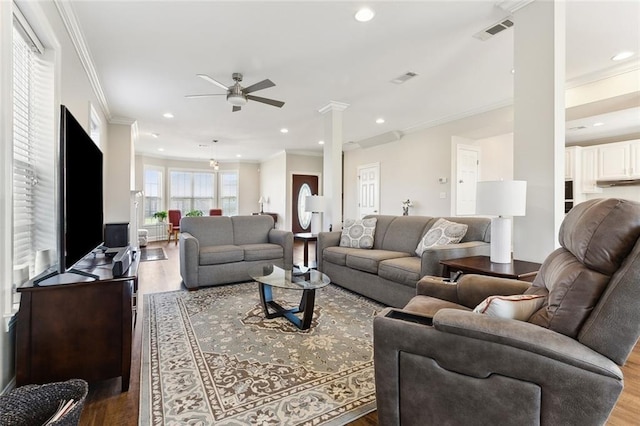 living room featuring ornate columns, visible vents, crown molding, and wood finished floors