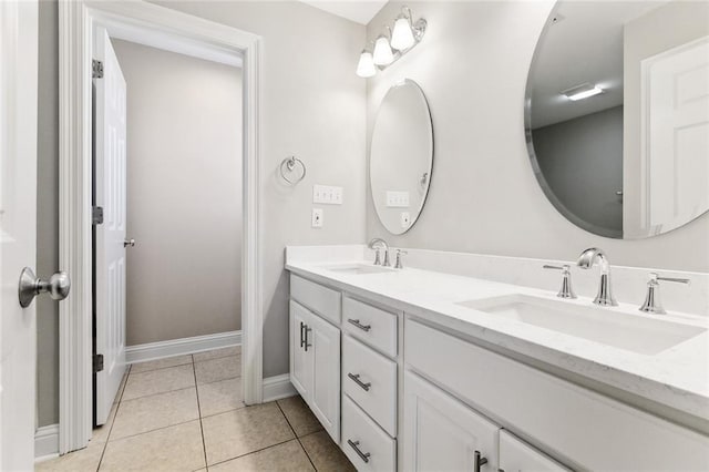 full bath with double vanity, tile patterned flooring, a sink, and baseboards