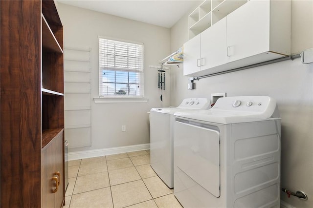 laundry area featuring light tile patterned floors, washing machine and dryer, baseboards, and cabinet space