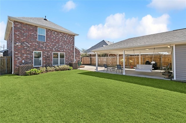 back of house featuring a patio area, a fenced backyard, a yard, and brick siding