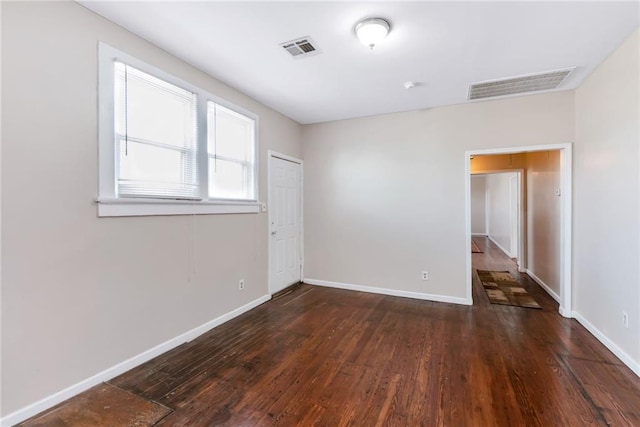 spare room with wood finished floors, visible vents, and baseboards