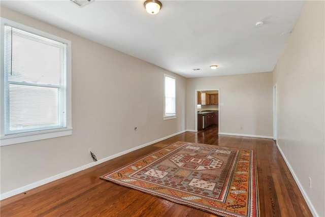 spare room with baseboards and wood finished floors