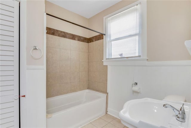 full bathroom featuring washtub / shower combination, wainscoting, a sink, and tile patterned floors