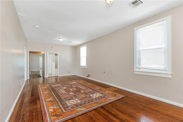 spare room with baseboards, visible vents, and wood finished floors