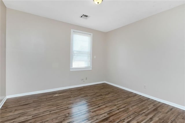 spare room with baseboards, visible vents, and wood finished floors