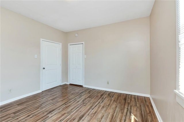 unfurnished room with baseboards and wood finished floors