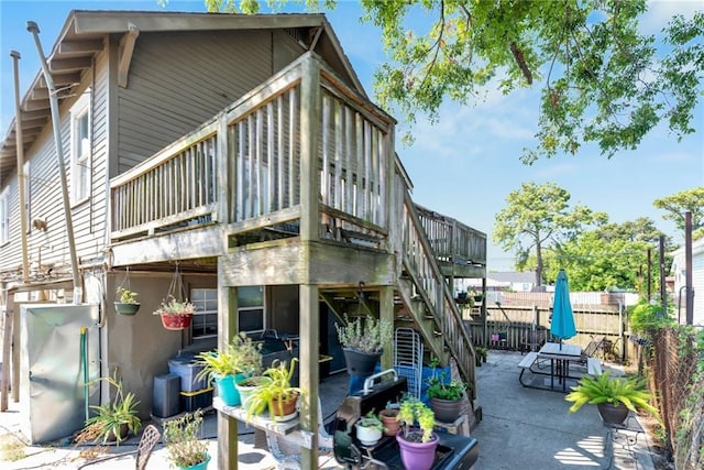 rear view of property featuring stucco siding, fence, stairway, and a patio