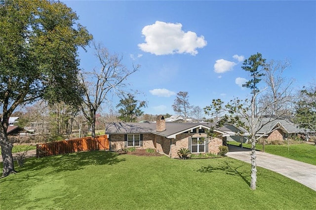 single story home featuring brick siding, fence, driveway, a chimney, and a front yard