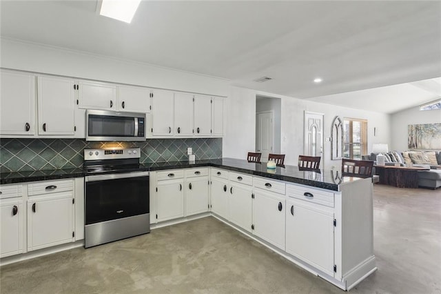 kitchen featuring white cabinets, concrete flooring, stainless steel appliances, a peninsula, and backsplash