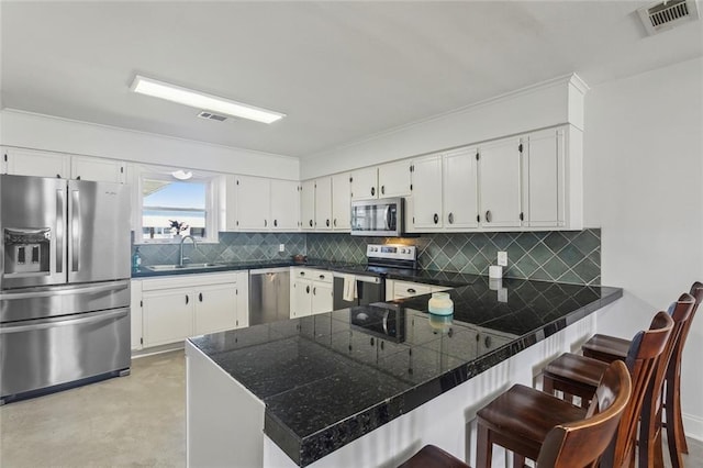 kitchen featuring a sink, stainless steel appliances, white cabinetry, a peninsula, and visible vents