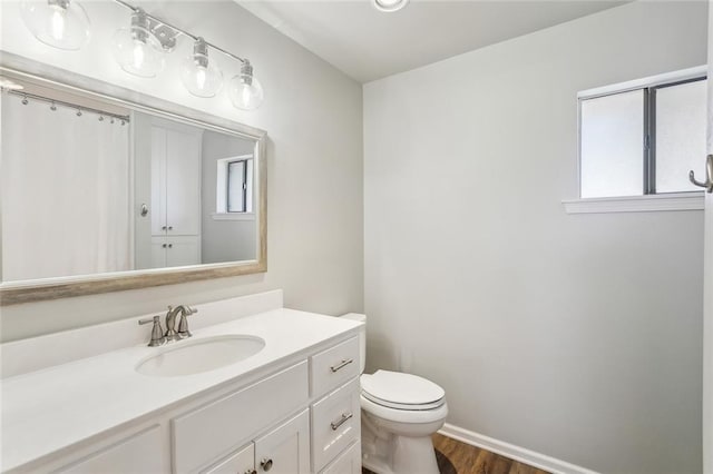 bathroom featuring toilet, baseboards, wood finished floors, and vanity