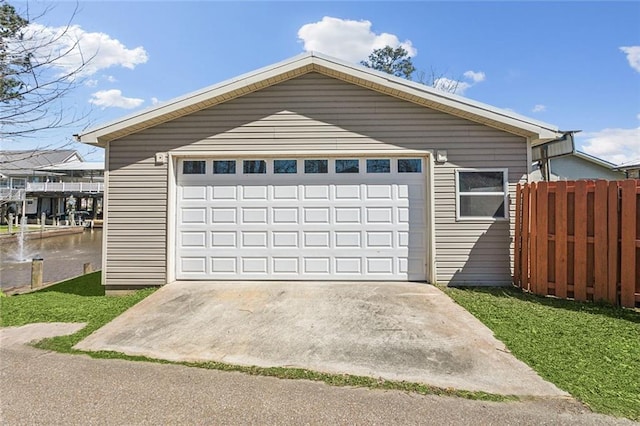 detached garage featuring a water view and fence