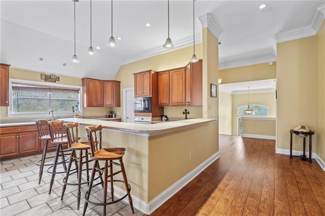 kitchen with baseboards, light wood-style flooring, ornamental molding, light countertops, and black microwave