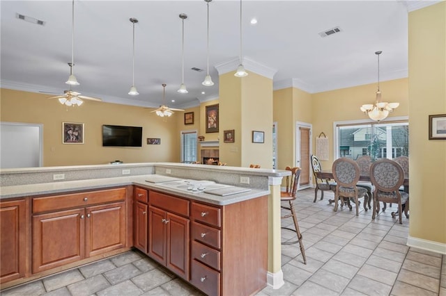 kitchen featuring light countertops, a warm lit fireplace, visible vents, and crown molding