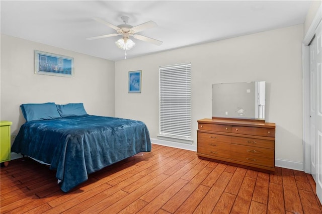 bedroom with baseboards, a closet, light wood-style flooring, and a ceiling fan