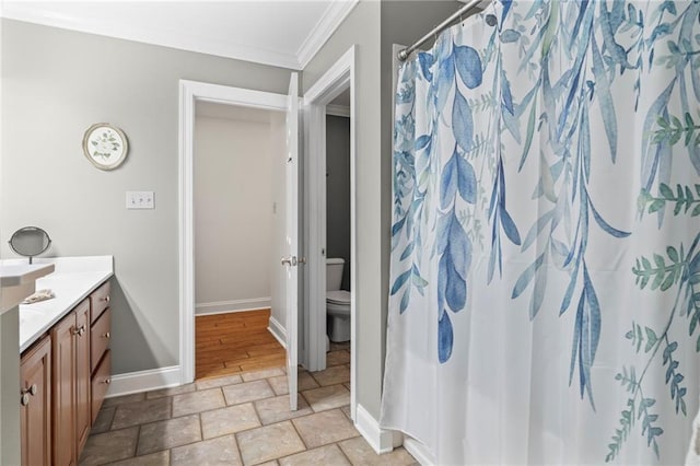 full bath featuring toilet, vanity, baseboards, ornamental molding, and stone finish floor