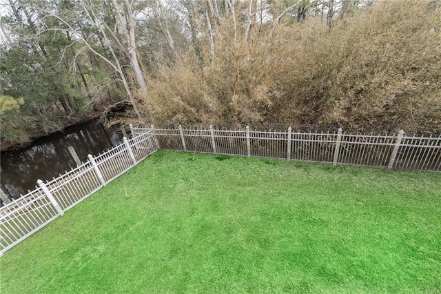 view of yard featuring a water view and a fenced backyard